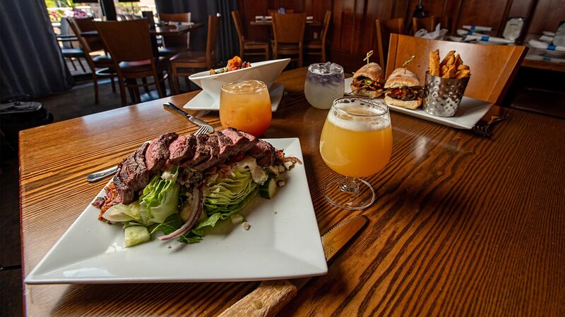 Steak wedge salad on a table with drinks and a steak sandwich